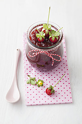 Jar of wild strawberry jam with spoon on white background - ECF000083