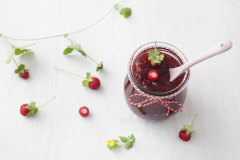 Glas Walderdbeermarmelade mit Löffel auf weißem Hintergrund, lizenzfreies Stockfoto