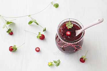 Jar of wild strawberry jam with spoon on white background - ECF000085
