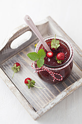 Jar of wild strawberry jam with spoon on white background - ECF000086