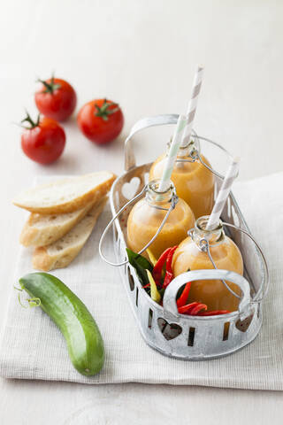 Flaschen mit Gazpacho mit Chilis, Brot und Tomaten auf Serviette, lizenzfreies Stockfoto