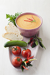 Bowl of gazpacho with bread, tomatoes, and chillies on tray - ECF000093