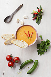 Bowl of gazpacho with bread, tomatoes, chillies and pickle on tray - ECF000095