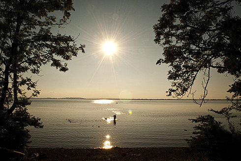 Deutschland, Bayern, Menschen beim Baden im Chiemsee bei Sonnenuntergang - KAF000016