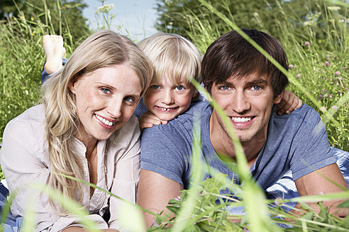 Deutschland, Köln, Familie auf der Wiese liegend, lächelnd, Porträt - PDYF000022