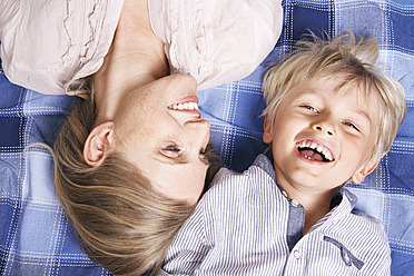 Germany, Cologne, Mother and son lying on blanket, smiling - PDYF000030