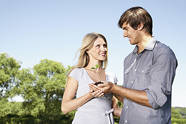 Germany, Cologne, Young couple holding seedling - PDYF000073