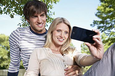 Germany, Cologne, Young couple taking self photograph, smiling - PDYF000100