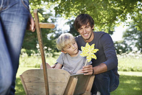 Deutschland, Köln, Vater und Sohn mit Papierwindmühle, lächelnd, lizenzfreies Stockfoto