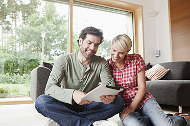 Germany, Bavaria, Nuremberg, Mature couple using digital tablet in living room - RBYF000135