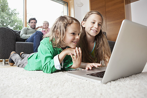 Deutschland, Bayern, Nürnberg, Mädchen und Junge benutzen Laptop im Wohnzimmer - RBYF000139
