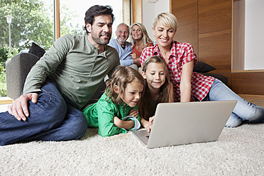 Germany, Bavaria, Nuremberg, Family using laptop in living room - RBYF000143