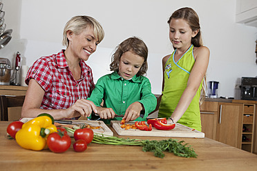 Germany, Bavaria, Nuremberg, Mother and children cutting vegetables - RBYF000154