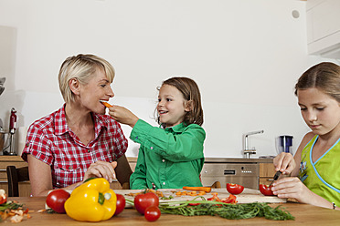 Germany, Bavaria, Nuremberg, Mother and children cutting vegetables - RBYF000156