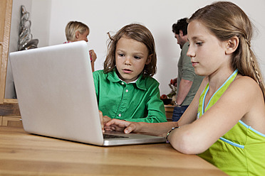 Deutschland, Bayern, Nürnberg, Mädchen und Junge benutzen Laptop in Küche - RBYF000157