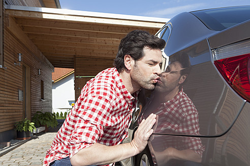 Germany, Bavaria, Nuremberg, Mature man kissing car - RBYF000185