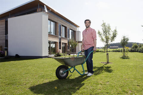 Deutschland, Bayern, Nürnberg, Älterer Mann mit Schubkarre im Garten, lizenzfreies Stockfoto