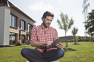 Deutschland, Bayern, Nürnberg, Älterer Mann benutzt digitales Tablet im Garten - RBYF000189