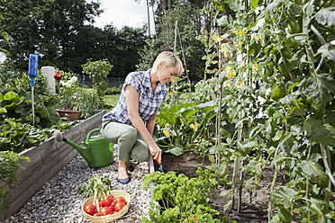 Deutschland, Bayern, Nürnberg, Reife Frau mit Gemüse im Garten - RBYF000203