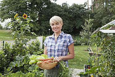 Deutschland, Bayern, Nürnberg, Reife Frau mit Gemüse im Garten - RBYF000204