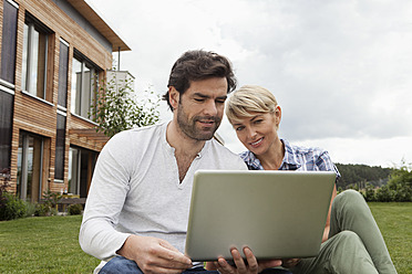 Deutschland, Bayern, Nürnberg, Älteres Paar mit Laptop im Garten - RBYF000210