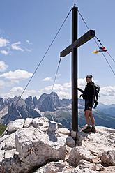 Italy, South Tyrol, Mid adult woman standing on mountain summit with cross at Mt. Petz - UMF000434