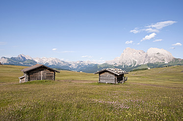 Italien, Blick auf Almhütten, Langkofel und Plattkofel im Hintergrund in Südtirol - UMF000400