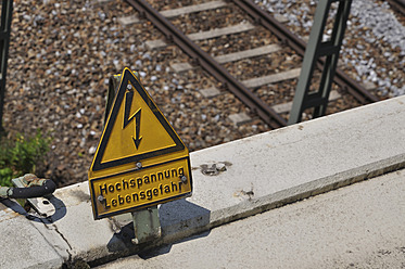 Deutschland, Bayern, Hochspannungsschild an der Bahnstrecke - AXF000244