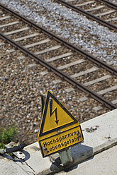 Deutschland, Bayern, Hochspannungsschild an der Bahnstrecke - AXF000245