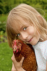 Germany, Brandenburg, Girl holding hen, smiling, portrait - BFRF000017