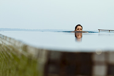 India, Kerala, Young woman relaxing in pool - MBEF000500