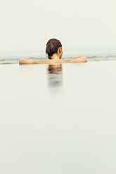 India, Kerala, Young woman relaxing in pool - MBEF000501