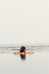 India, Kerala, Young woman relaxing in pool - MBEF000503