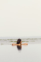 Indien, Kerala, Junge Frau entspannt im Pool - MBEF000503