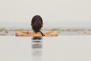 Indien, Kerala, Junge Frau entspannt im Pool - MBEF000504