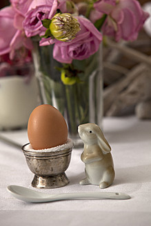 Ei im Eierbecher mit Hasenfigur, Glas mit Blumen im Hintergrund - KRF000026