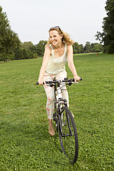 Deutschland, Berlin, Junge Frau mit ihrem Fahrrad im Treptower Park - FKF000055