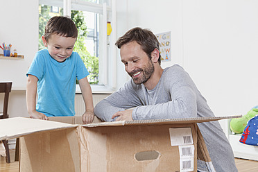 Germany, Berlin, Father and son opening parcel box - RBF000956