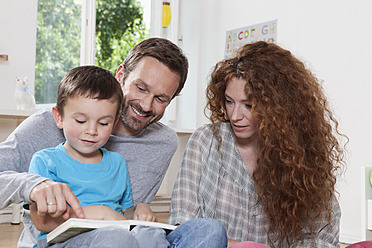 Deutschland, Berlin, Familie liest Buch zu Hause - RBF000959