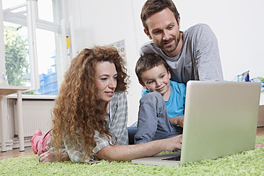 Deutschland, Berlin, Familie benutzt Laptop auf dem Boden - RBF000973