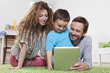 Deutschland, Berlin, Familie benutzt digitales Tablet auf dem Boden - RBF000974