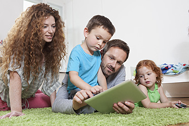 Deutschland, Berlin, Vater benutzt digitales Tablet mit Familie auf dem Boden - RBF000975