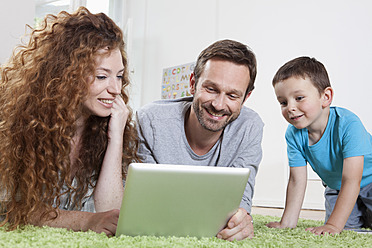 Deutschland, Berlin, Familie benutzt digitales Tablet auf dem Boden - RBF000976