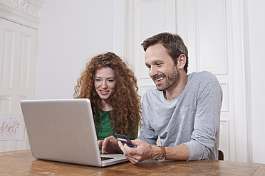 Deutschland, Berlin, Pärchen nutzt Laptop zum Homeshopping - RBF001000