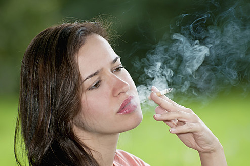 Deutschland, Berlin, Junge Frau raucht Zigarette im Park - BFRF000062