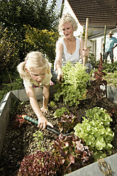 Germany, Bavaria, Grandmother with children working in vegetable garden - RNF001024