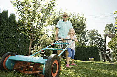 Germany, Bavaria, Grandfather with children mowing lawn - RNF001031