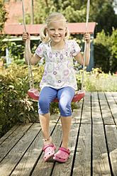 Germany, Bavaria, Girl swinging on swing, smiling, portrait - RNF001032