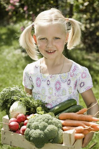 Deutschland, Bayern, Mädchen hält Gemüse in Kiste, lächelnd, Porträt, lizenzfreies Stockfoto