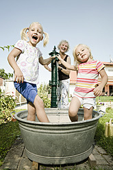 Deutschland, Bayern, Großmutter mit spielenden Kindern im Wasserbottich - RNF001045